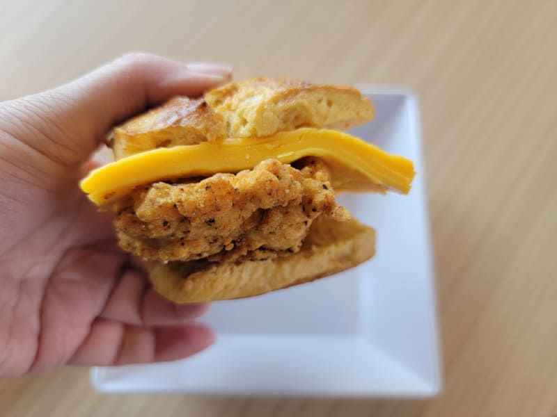 hand holding a biscuit with cheese and chicken