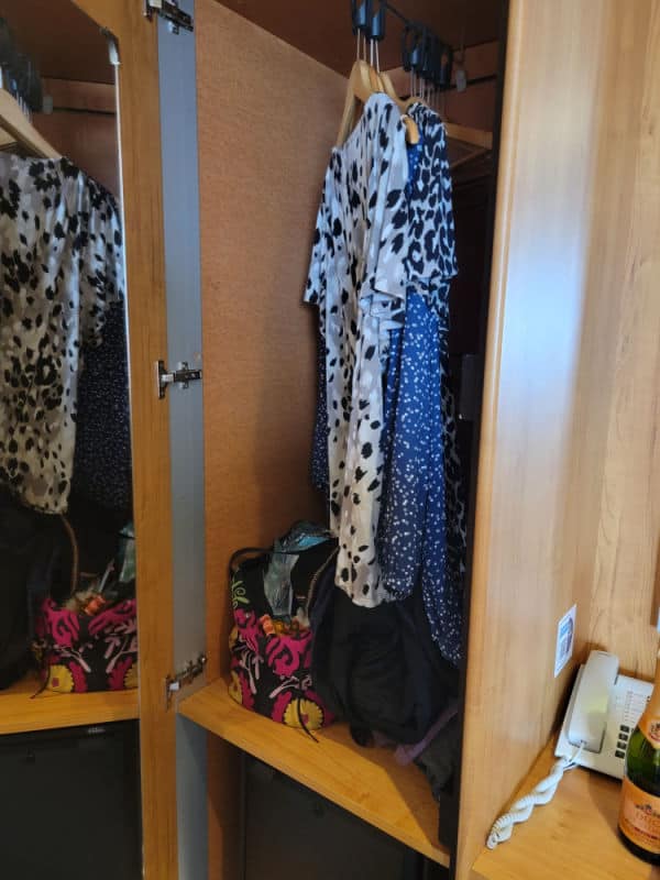 Shirts hanging in a closet next to a phone