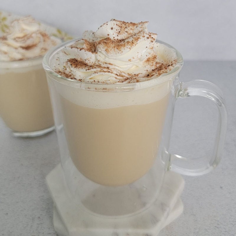Eggnog coffee with a whipped cream garnish and cinnamon in a glass mug