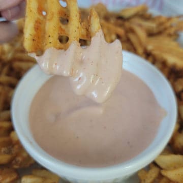 Waffle fry dipping into a bowl of homemade fry sauce