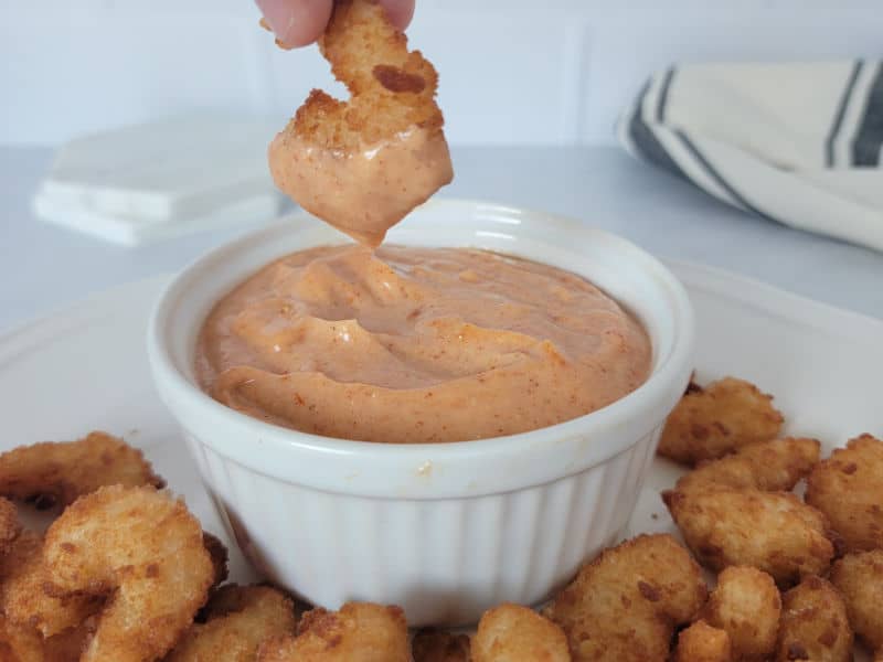 Air fryer shrimp dipping into a white bowl filled with homemade Yum Yum Sauce