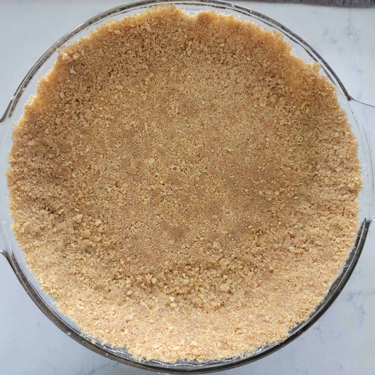 Graham cracker crust in a glass baking dish