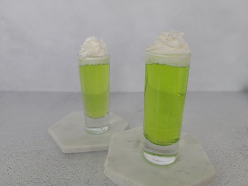 2 Bright Green Scooby Snack Shots in clear shot glasses with whipped cream garnish