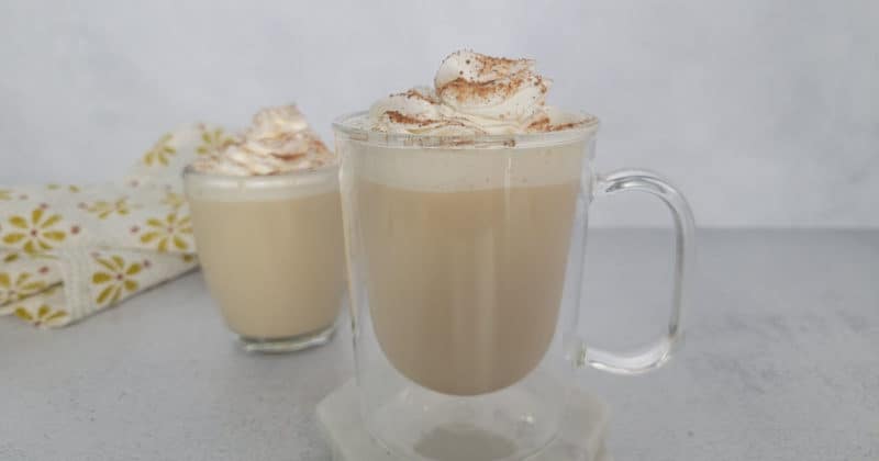 Eggnog coffee with a whipped cream garnish and cinnamon in a glass mug