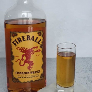Fireball shot in a glass next to a bottle of Fireball