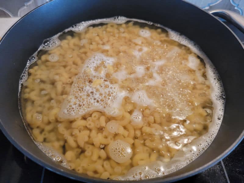 Macaroni cooking in a dark skillet on the stove top