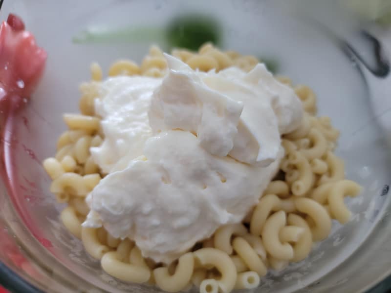 Large dollop of mayo on cooked macaroni in a glass bowl 