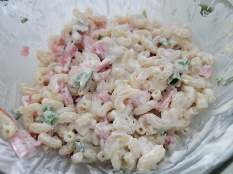 Mayo covered macaroni and tomatoes in a glass bowl 