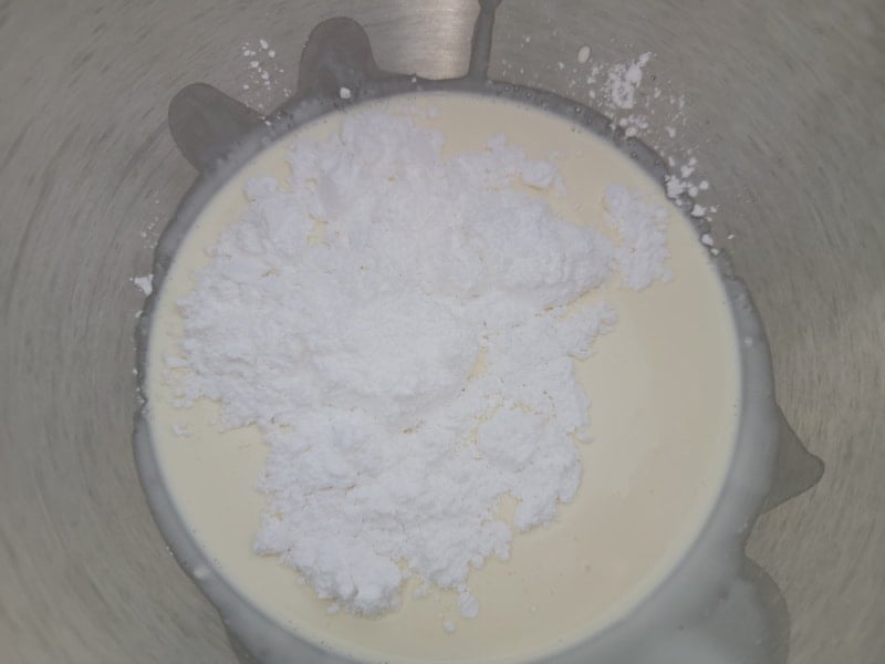 Heavy whipping cream and Confectioners sugar in a metal mixing bowl