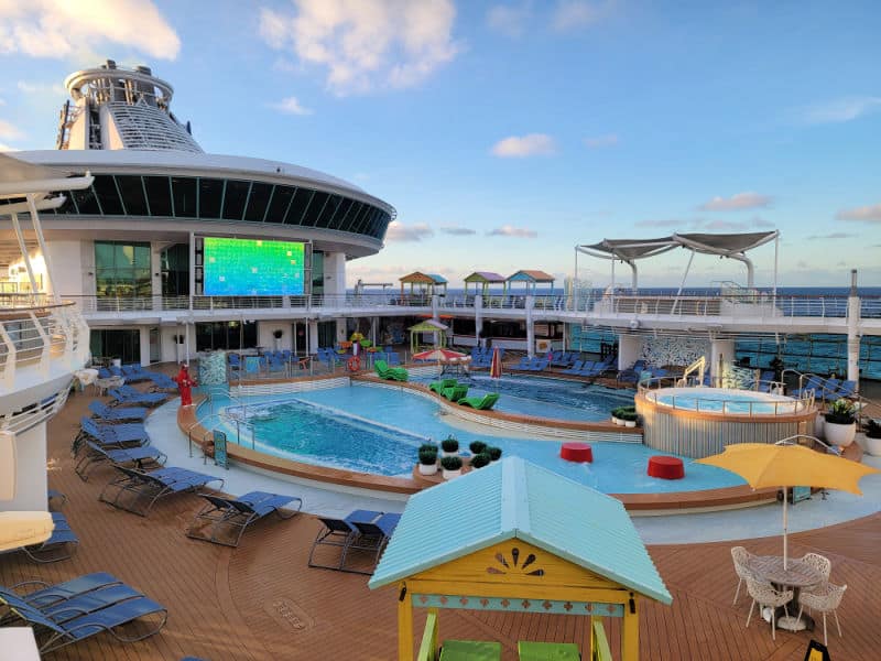 Pool deck with a hot tub, movie screen, and lounge chairs with a view of the ocean. 