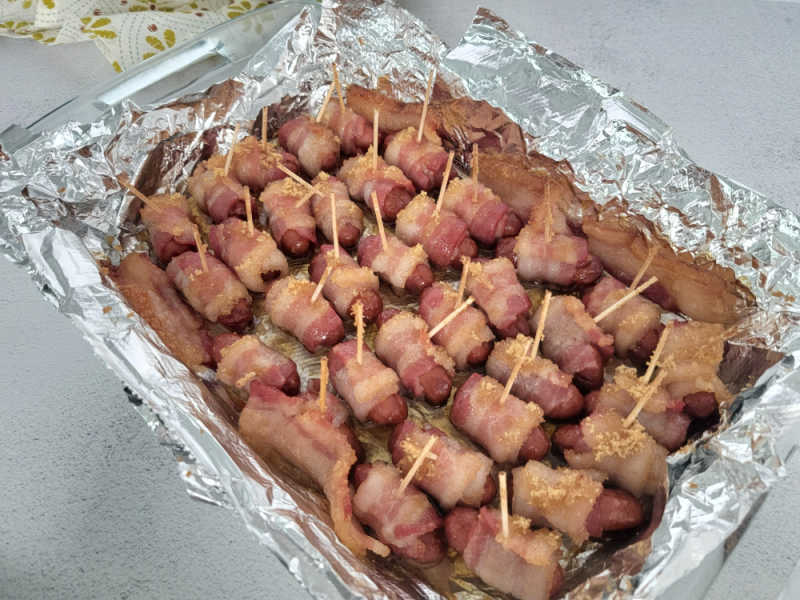 Baked Bacon wrapped lit'l smokies in an aluminum foil baking dish