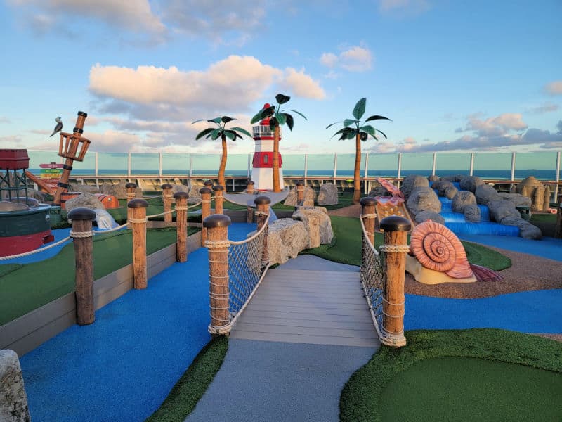 Putt Putt golf with a lighthouse, fake palm trees and a view of the ocean. 