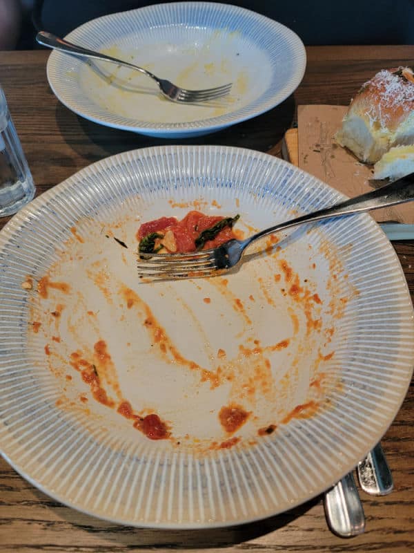 Empty plate with remnants of tomato sauce and a fork