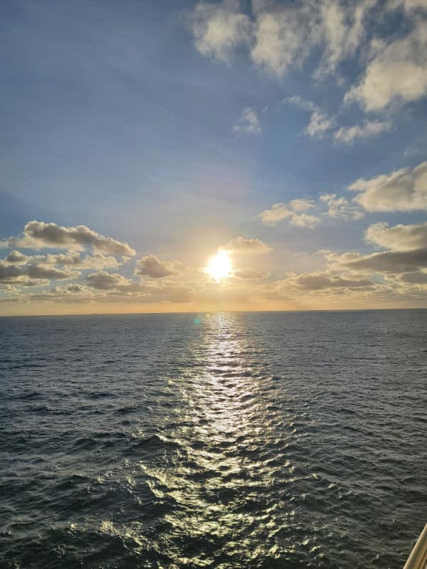 Sunset over the ocean with fluffy white clouds