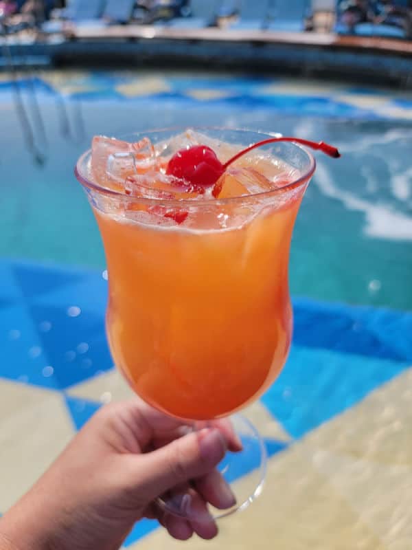 Tropical cocktail being held near a pool 