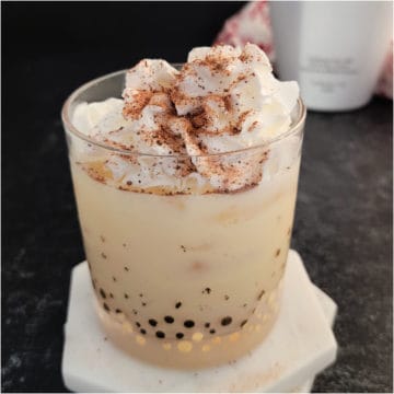 RumChata Eggnog Cocktail garnished with whip cream and nutmeg on white coasters