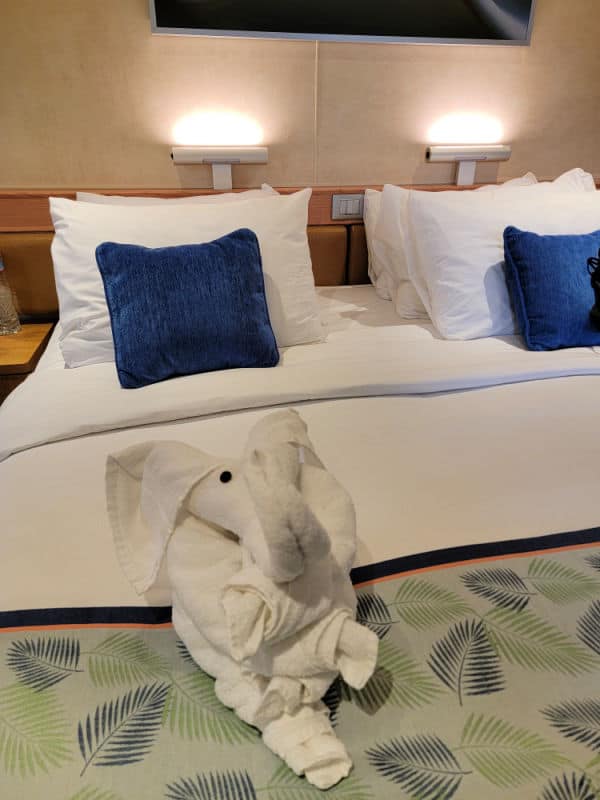 Towel animal elephant on a tropical bedspread with blue and white pillows