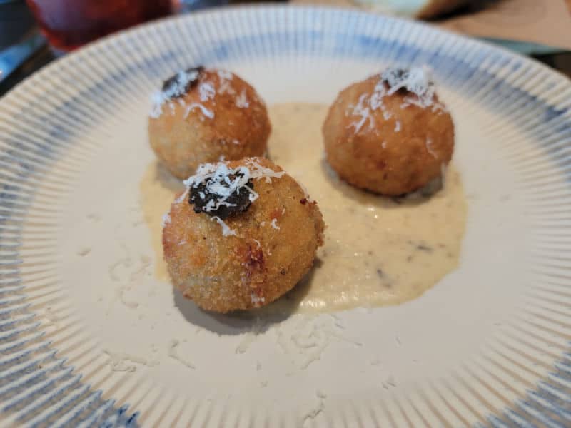 rice balls on a white plate with sauce