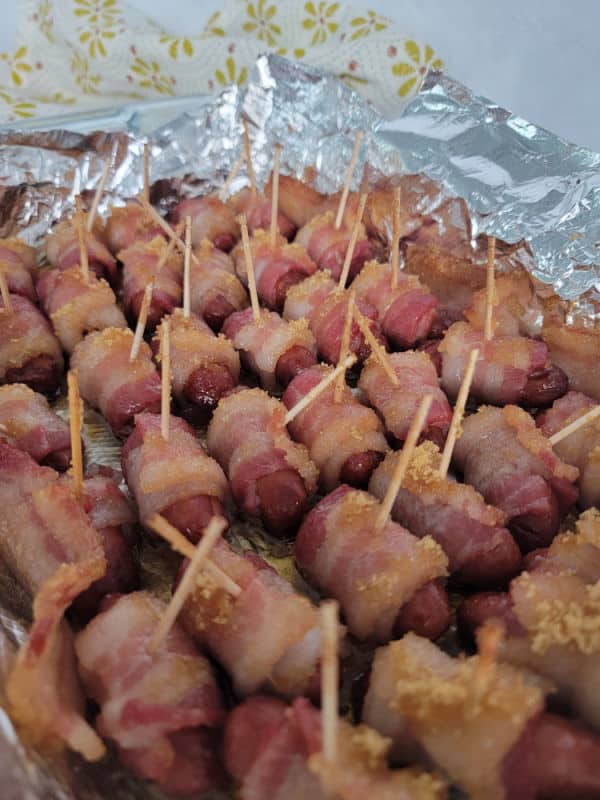 Baked Bacon Wrapped little smokies in an aluminum foil lined baking dish