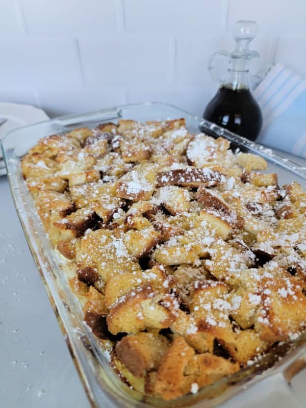 Overnight French Toast breakfast casserole in a glass baking dish with maple syrup