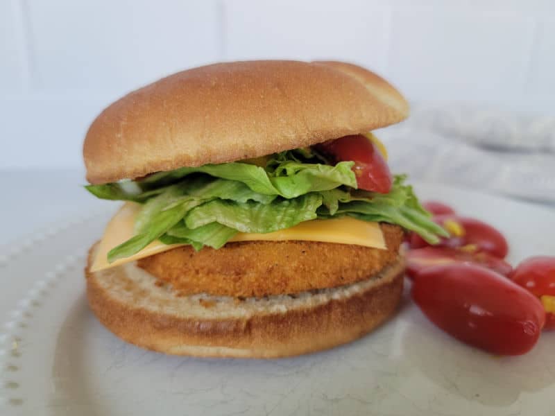 air fried chicken burger on a bun with lettuce, tomato, and cheese