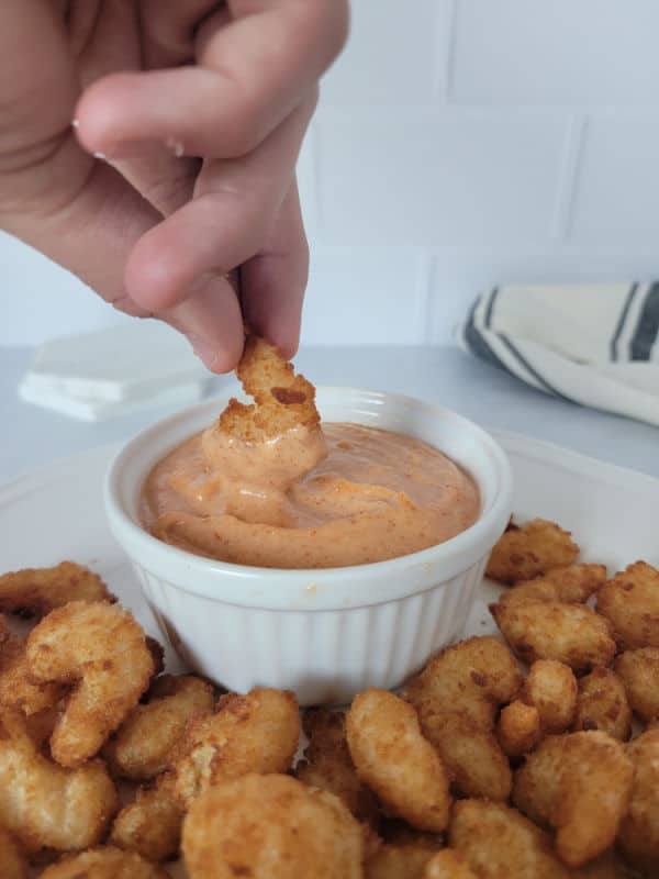 Air fryer shrimp being dipped into a bowl of homemade Yum Yum Sauce 