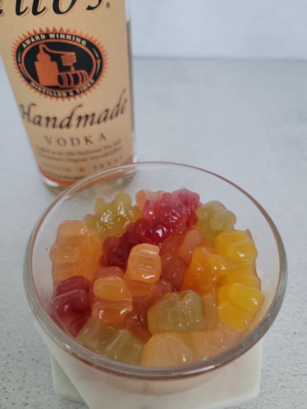 gummy bears in a glass bowl next to a bottle of Tito's Vodka