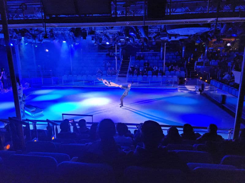 ice skater being spun in the air while on an ice rink with blue lights