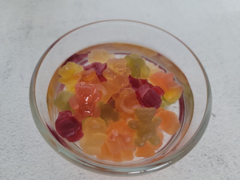 Gummy bears floating in clear liquid in a glass bowl