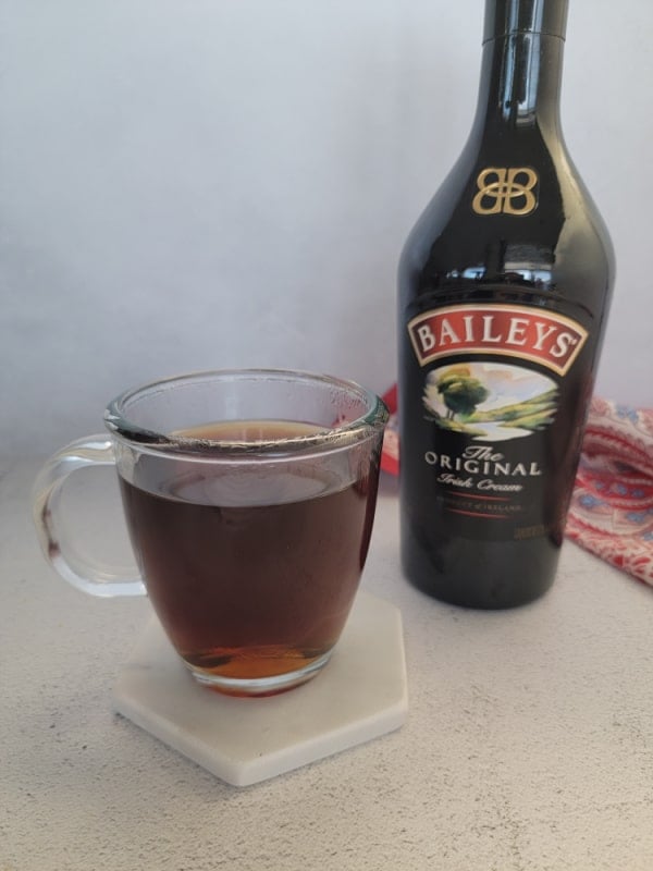 Coffee in a glass mug next to a bottle of Baileys Irish Cream 