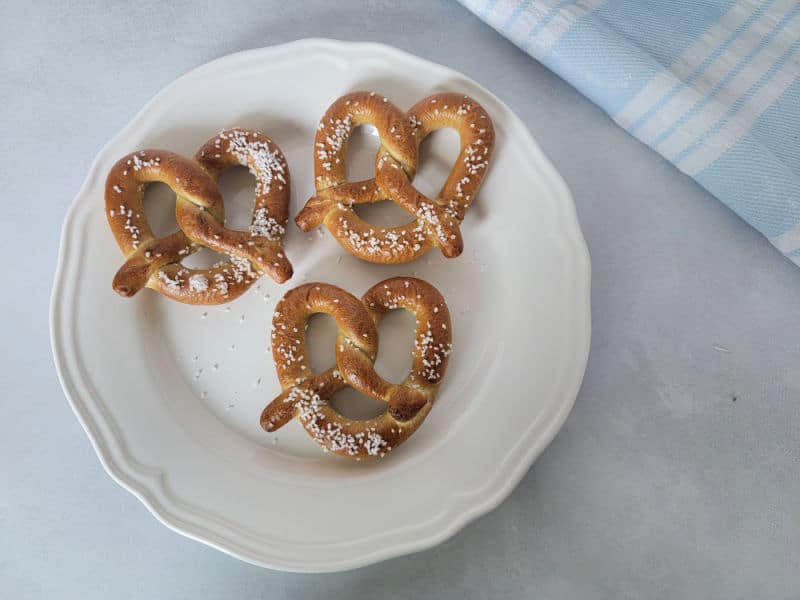 Air fried pretzels on a white plate by a cloth napkin