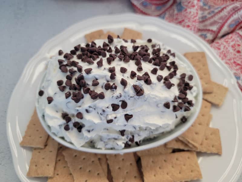 Booty dip with mini chocolate chips in a white bowl surrounded by graham crackers 