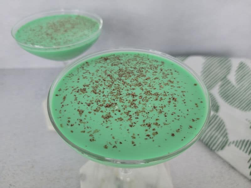 Green cocktails with chocolate shavings on them next to a cloth napkin