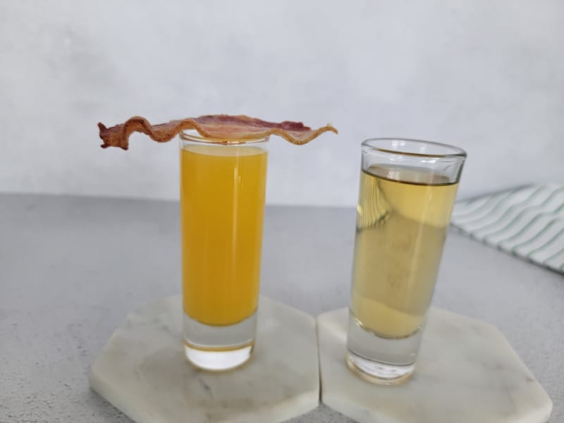 Irish Breakfast shot with bacon on top of orange juice next to a filled shot glass