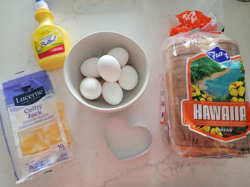 colby jack cheese, butter, eggs, a heart cookie cutter, and loaf of bread