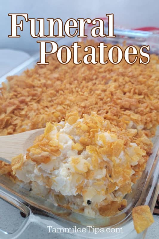 Funeral Potatoes over a glass baking dish with a wooden spoon scooping potatoes
