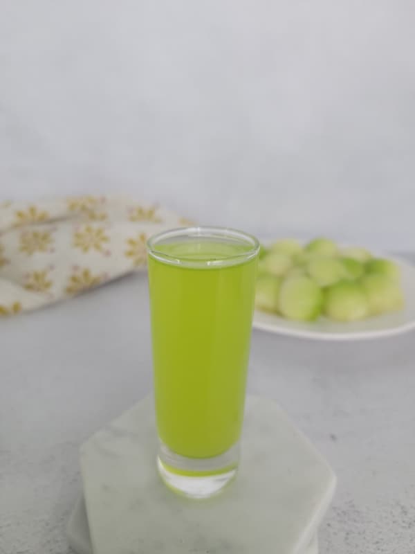 Melon Ball shot on a white coaster next to a plate of melon balls