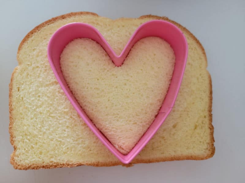 heart cookie cutter going into a slice of bread