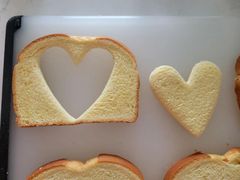 heart cut out of a piece of bread on a cutting board