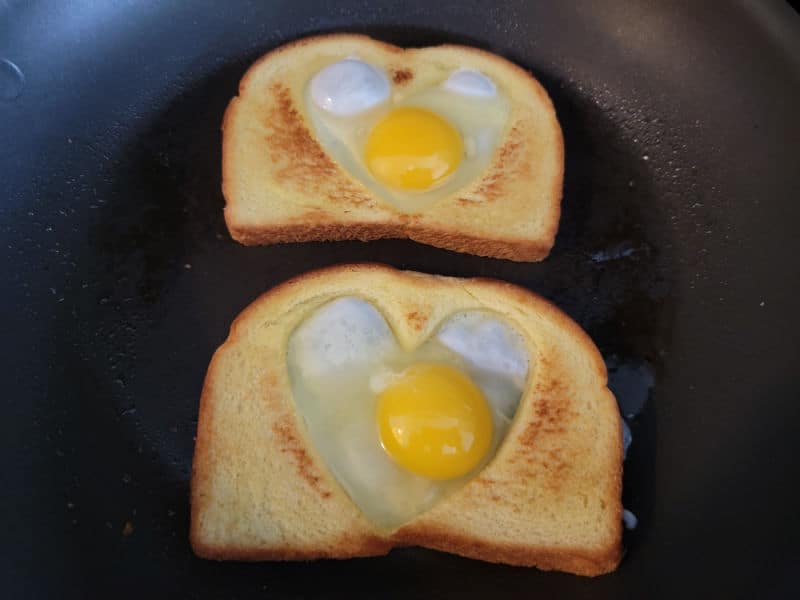 eggs in the heart cut out of two slices of bread in a skillet 