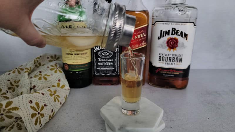 Mason jar cocktail shaker pouring into a shot glass