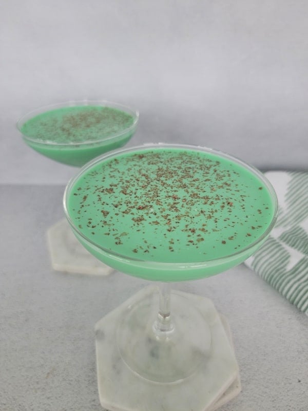 Green cocktails in coupe glasses sitting on marble coasters