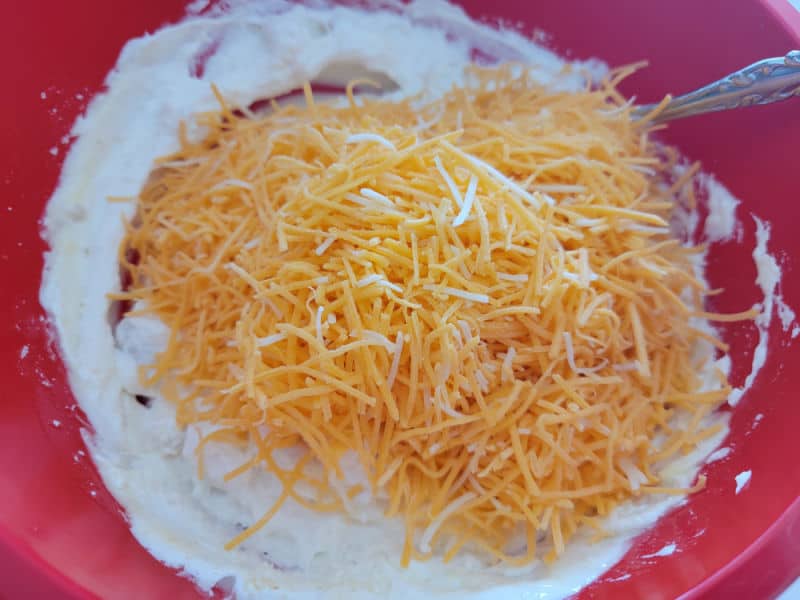shredded cheese with ingredients in a red bowl 