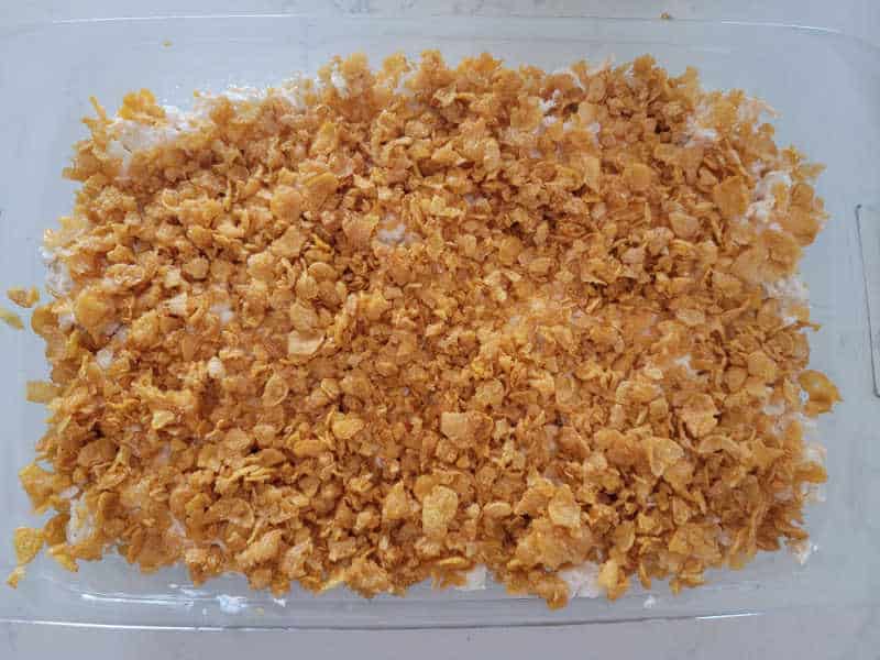 Crushed cornflakes spread over potatoes in a glass baking dish