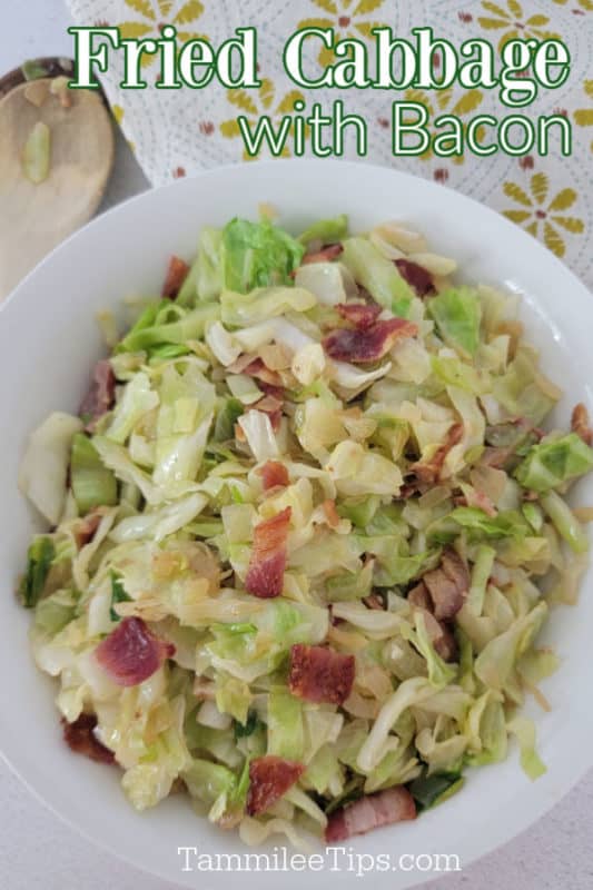 Fried Cabbage with bacon over a white bowl with cabbage and bacon next to a wooden spoon and cloth napkin