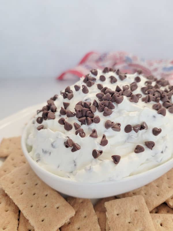 Booty dip with mini chocolate chips in a white bowl surrounded by graham crackers