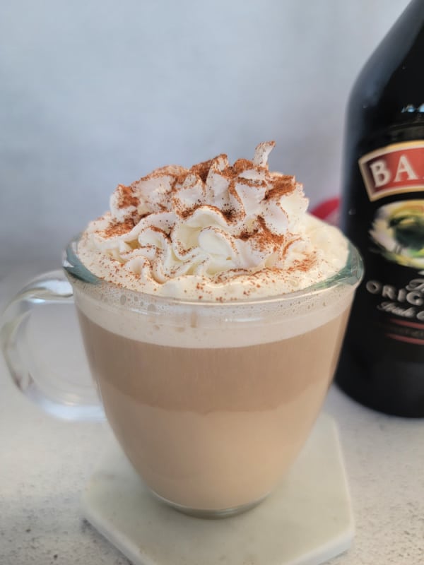 Baileys Coffee in a glass mug next to a bottle of Baileys