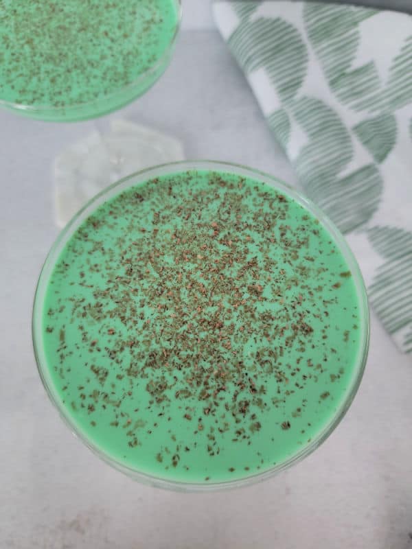 Looking down into a green cocktail with chocolate shavings floating as a garnish