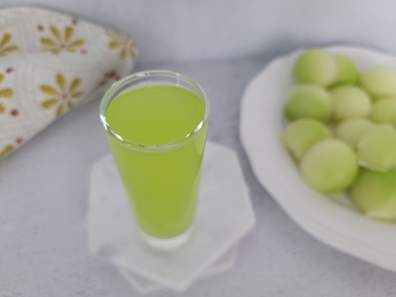 Melon Ball shot in a cocktail glass next to a plate of melon balls