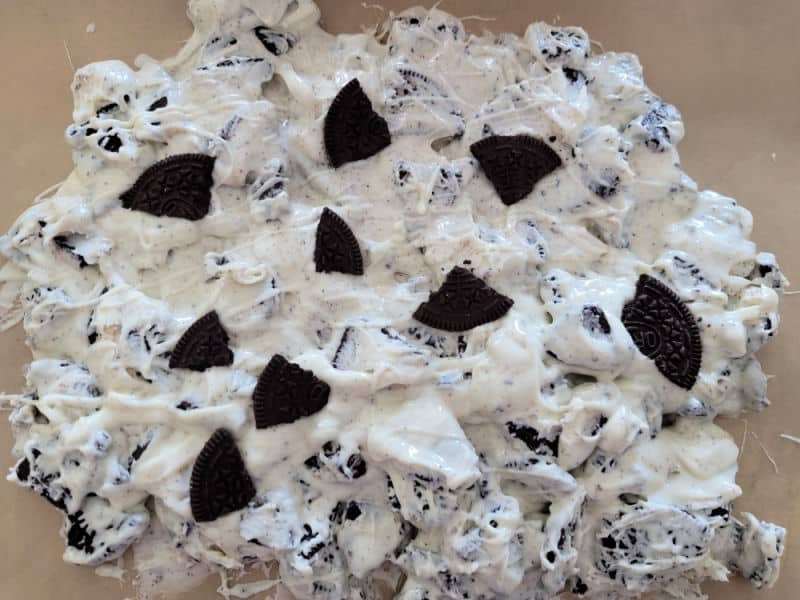 Oreos and melted white chocolate spread on parchment paper 